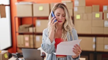 Genç sarışın kadın ecommerce iş işçisi ofisteki akıllı telefon okuma belgesiyle konuşuyor.