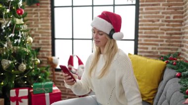 Evde Noel 'i kutlamak için telefon dinleyen genç sarışın kadın.