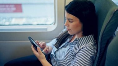 Trenin içinde akıllı telefon kullanan genç ve güzel bir İspanyol kadın.