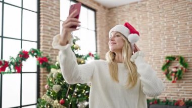 Sarışın genç bir kadın Noel 'i evde kutlarken selfie çekiyor.