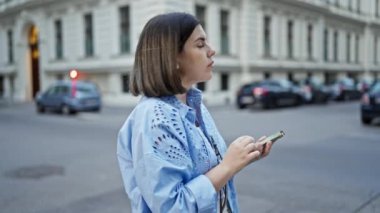 Genç ve güzel İspanyol kadın akıllı telefon kullanıyor. Viyana sokaklarında birilerini bekliyor.