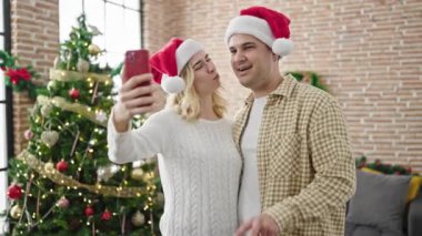 Noel 'i kutlayan erkek ve kadın çifti evde akıllı telefonlardan selfie çekiyor.