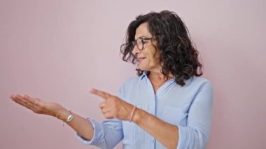 Orta yaşlı İspanyol kadın gülümsüyor. Yan tarafı gösteriyor. İzole edilmiş pembe arka planı gösteriyor.