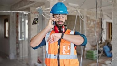 İnşaat alanında akıllı telefondan konuşan genç İspanyol mimar.
