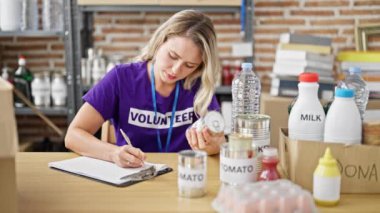 Genç sarışın kadın gönüllü olarak hayır kurumunda yemek listesini kontrol ediyor.