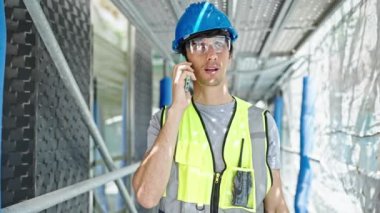 Genç İspanyol mimar inşaat alanında akıllı telefondan konuşuyor.