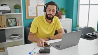 Genç İspanyol iş adamı ofiste müzik dinleyip dans ediyor.