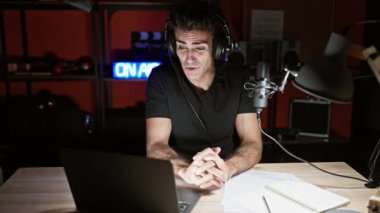 Genç İspanyol bir adam radyo stüdyosunda radyo programında konuşuyor.
