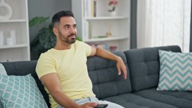 Erkek ve kadın çift birbirlerine sarılıyorlar ve evde televizyon izliyorlar.
