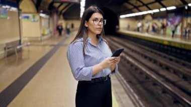 Madrid metro istasyonunda akıllı telefon kullanan güzel İspanyol bir kadın metroda bekliyor.