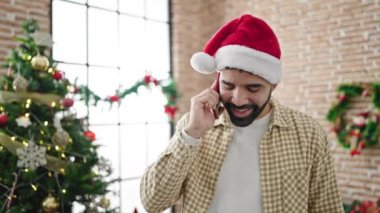 Genç İspanyol adam Noel 'i kutluyor ve evde akıllı telefondan konuşuyor.