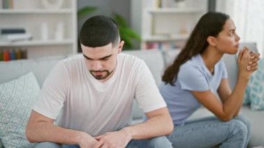 Stresli, güzel bir çift ciddi bir anlaşmazlık içinde, evlerindeki oturma odasındaki kanepede oturuyorlar, üzgün ve sessiz görünüyorlar.