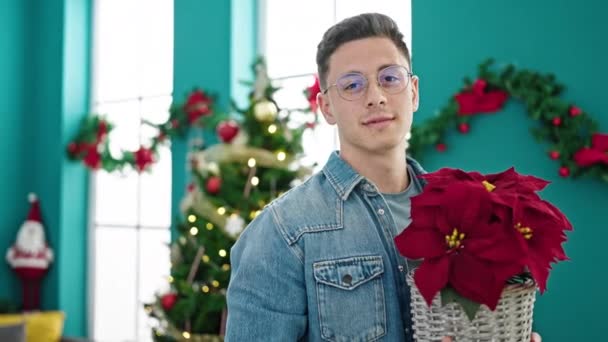 Νεαρός Ισπανός Που Κρατάει Χριστουγεννιάτικο Φυτό Χαμογελώντας Στο Σπίτι — Αρχείο Βίντεο
