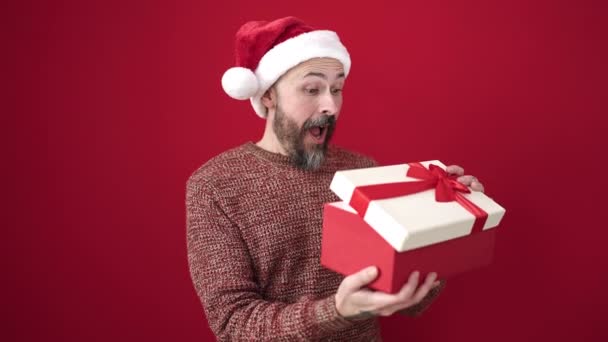 Jonge Kale Man Draagt Kerstmuts Uit Pakken Geschenk Geïsoleerde Rode — Stockvideo