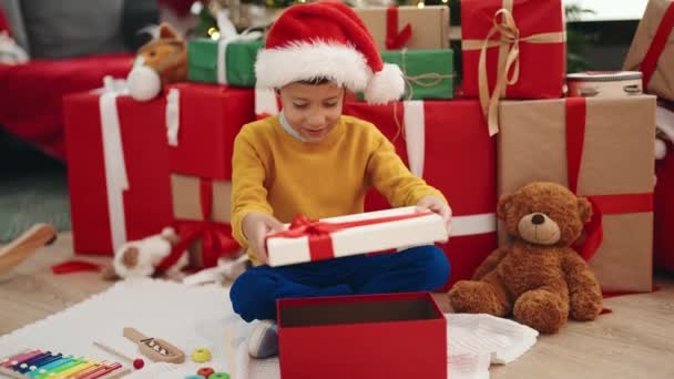 Adorable Hispanic Boy Unpacking Gift Sitting Christmas Tree Home — Stock Video