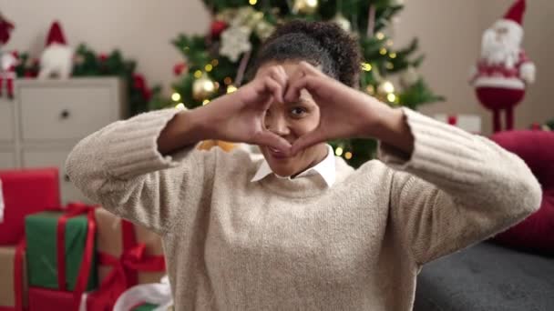 Mujer Afroamericana Haciendo Gesto Corazón Sentado Sofá Por Árbol Navidad — Vídeos de Stock