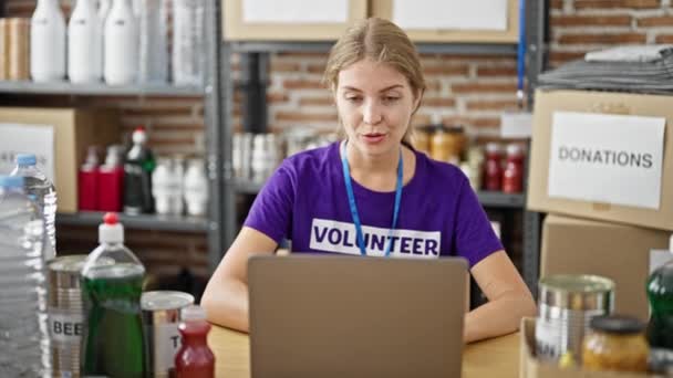 Joven Mujer Rubia Voluntaria Teniendo Videollamada Sentada Mesa Centro Caridad — Vídeos de Stock