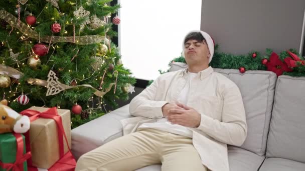 Νεαρός Ισπανός Γιορτάζει Χριστούγεννα Καθισμένος Στον Καναπέ Στομαχόπονο Στο Σπίτι — Αρχείο Βίντεο