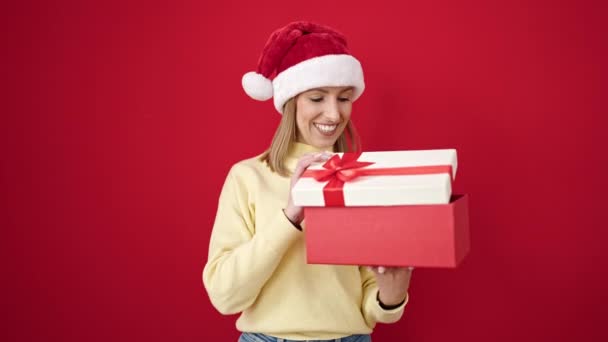 Jong Blond Vrouw Uitpakken Kerstcadeau Kijken Boos Geïsoleerde Rood Achtergrond — Stockvideo