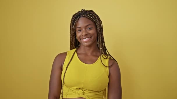 アフリカ系アメリカ人女性 孤立した黄色の背景の上に自信を持って吹くキスを微笑む — ストック動画