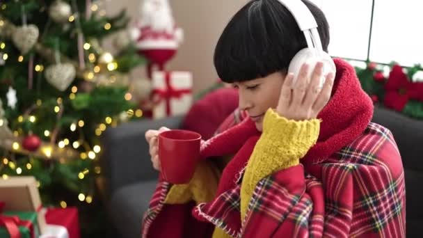Ung Kinesisk Kvinna Lyssnar Musik Dricka Kaffe Vid Julgranen Hemma — Stockvideo
