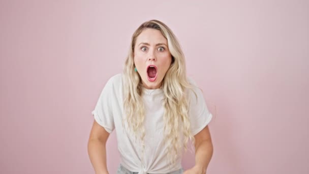 Młoda Blondynka Stoi Zaskakującym Wyrazem Twarzy Odizolowanym Różowym Tle — Wideo stockowe