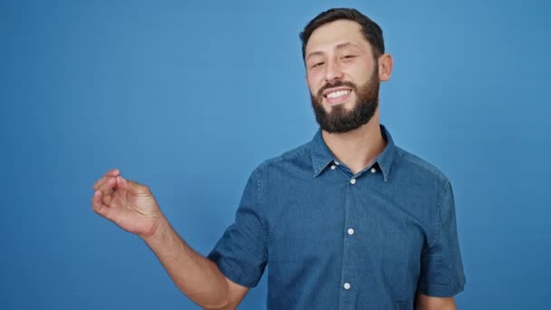 Joven Hombre Hispano Sonriendo Señalando Lado Sobre Fondo Azul Aislado — Vídeo de stock