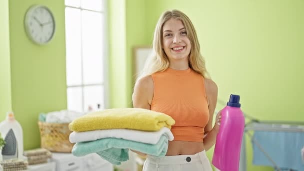 Młoda Blondynka Uśmiecha Się Pewnie Trzymając Złożone Ręczniki Detergent Pralni — Wideo stockowe
