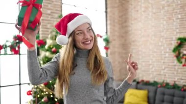 Genç Kafkasyalı kadın elinde Noel hediyesi tutarak evde dans ediyor.