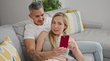 Kadın ve erkek evde akıllı telefon beşliği kullanıyor.