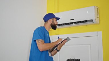 Genç İspanyol teknisyen evdeki havalandırma makinesini tamir ediyor.
