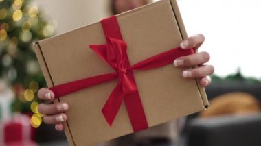 Sarışın genç bir kadın Noel ağacının yanında duruyor.
