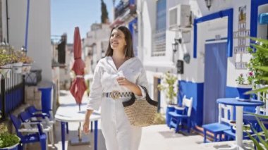 Genç ve güzel İspanyol kadın gülümsüyor ve tipik İspanyol kasabasına bakıyor.