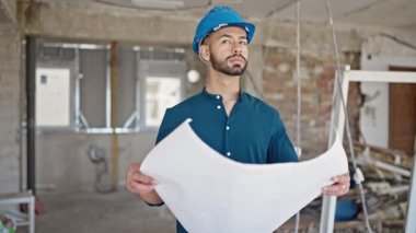 İspanyol asıllı genç mimar inşaat alanının planlarına bakıyor.