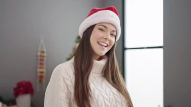 Genç ve güzel İspanyol kadın Noel ağacının yanında durmuş evde dans ediyor.