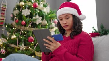 Genç ve güzel İspanyol kadın Noel alışverişini akıllı telefon ve kredi kartıyla yapıyor.