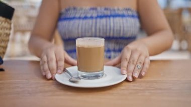 Genç İspanyol kadın kahvesini karıştırıyor güneşli restoran terasında masada oturuyor.