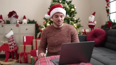 Kafkasyalı genç adam evdeki bilgisayarlı bir video çağrısında hediye gösteriyor.