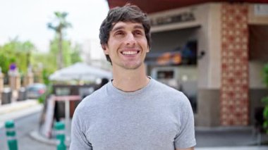 Sokakta kendinden emin gülümseyen İspanyol genç adam.