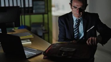 Orta yaşlı bir iş adamı ofiste çalışmayı bitiriyor.