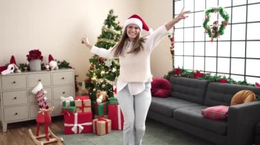 Genç ve güzel İspanyol kadın Noel ağacının yanında dans ediyor.