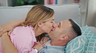 Man and woman couple hugging each other lying on sofa at home