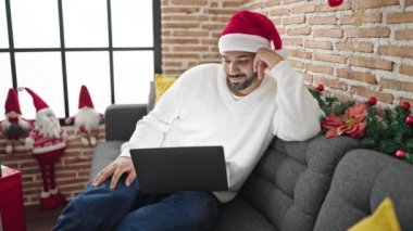 Evde Noel 'i kutlamak için dizüstü bilgisayardan video izleyen Afrikalı Amerikalı bir adam.