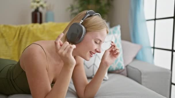 Młoda Blondynka Słuchająca Muzyki Leżącej Kanapie Domu — Wideo stockowe