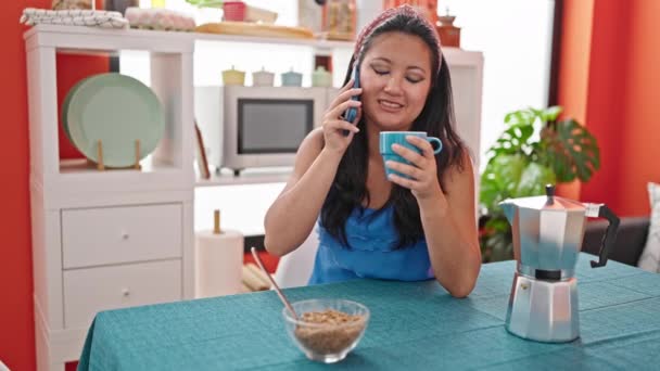 ダイニングルームでスマートフォンで朝食を食べている若い中国人女性 — ストック動画