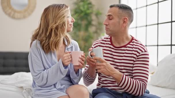 男人和女人坐在床上喝咖啡 在卧室里讲话 — 图库视频影像