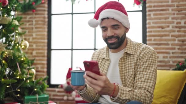 Młody Hiszpan Przy Użyciu Smartfona Pije Kawę Świętując Boże Narodzenie — Wideo stockowe