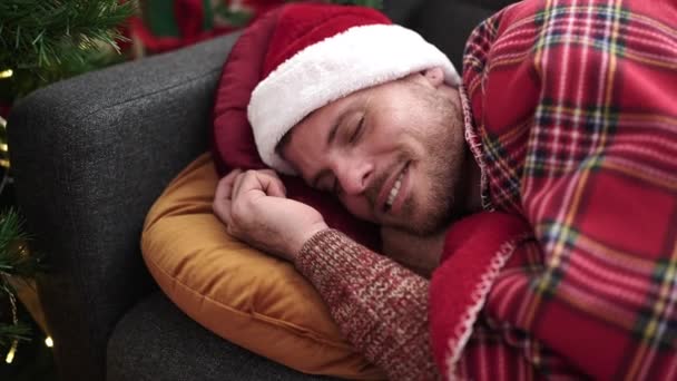 年轻的高加索男人躺在沙发上睡觉 戴着圣诞礼帽 — 图库视频影像
