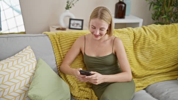 Young Blonde Woman Using Smartphone Doing Gesture Home — Stockvideo