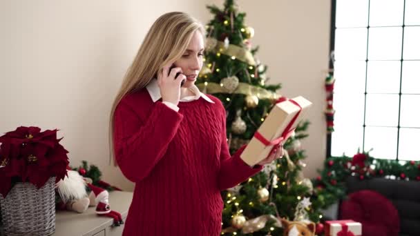 Mujer Rubia Joven Hablando Teléfono Inteligente Celebración Regalo Navidad Casa — Vídeos de Stock